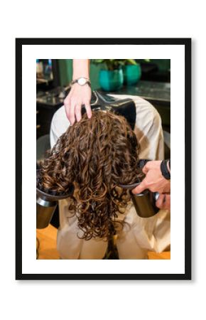 two hair dryers dry curly hair of a girl