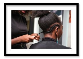 Hairdresser braiding client's afro hair in salon