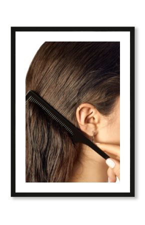 A person is gently combing through wet, dark brown hair using a black comb