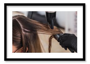 Professional female hairdresser drying woman's hair styling using blow dryer at the hairdressing saloon
