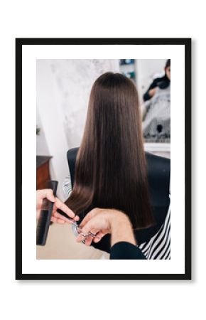 Young girl enjoying at hairstyle treatment while professional hairdresser gently working and cutting her hair.