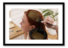 Professional hairdresser dyeing woman's hair with henna in beauty salon