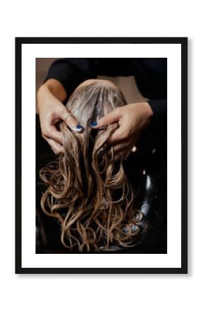 Hairdresser in beauty salon washes his client hair, before procedure of applying natural restoring ingredients and vitamins to hair and haircut.