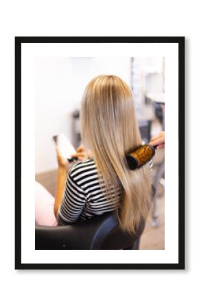 Blonde woman with long hair and with a phone in her hands at hairdressing salon.
