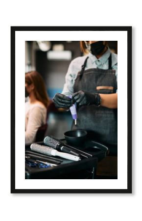 Close-up of hairdresser squeezing hair color from tube at hair salon.