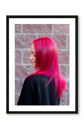 Young beautiful woman with pink hair on brick wall background