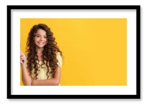 happy child with long curly hair holding comb hairbrush for combing, beauty. Kid girl hair care, horizontal poster. Banner header with copy space.