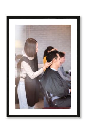 Asian woman hairstylist using scissors and comb for hair cut and design on man's hair in barbershop.