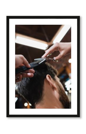hairdresser cutting hair of brunette man with thinning scissors.