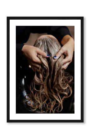 Hairdresser in beauty salon washes his client hair, before procedure of applying natural restoring ingredients and vitamins to hair and haircut.