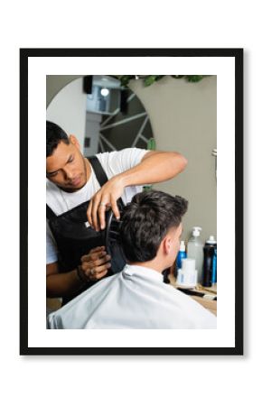  Young Latin American at work providing his services to clients. Colombian person working in his business. Barber doing a haircut to a client. Hairdressing service performed by a man.