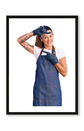 Young hispanic woman with tattoo wearing barber apron and gloves smiling making frame with hands and fingers with happy face. creativity and photography concept.