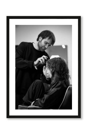 male hairdresser fixing hair of young woman with hairspray.