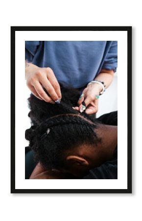 Close-up of a hairdresser braiding an African girl's hair