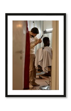 Vertical image of hairdresser doing haircut for customer in hair salon