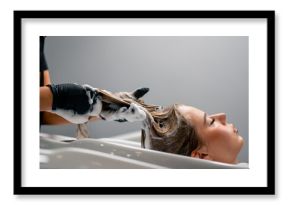 a hairdresser washing off dye from a client's hair during a care procedure in a beauty salon