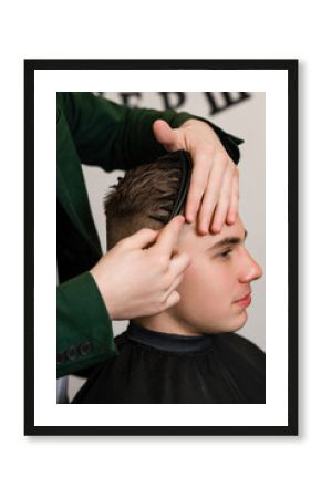 Haircut of a visitor in a barbershop. Hair styling with a comb, combing the client's hair by a stylist.
