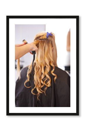 Back view, curls and hairdresser with curling iron for hair care, maintenance and styling for makeover. Balayage, waves and curly hairstyle, people and professional hairstylist at salon for beauty