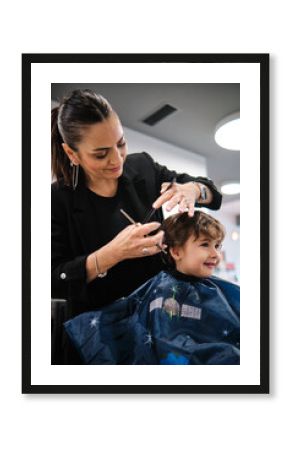 Woman hairdresser cutting a child's hair with comb and scissors in a salon