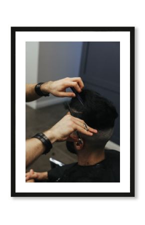 Male barber combing and shaving hair of a male client