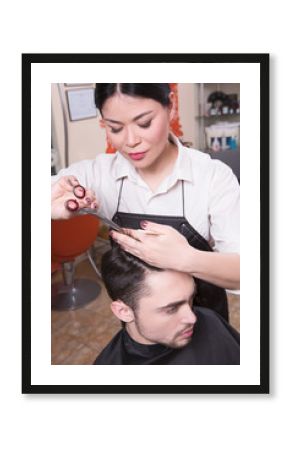 Young man in beauty saloon. Cropped shot of female hairdresser cutting man's hair with scissors at hairdressing salon.