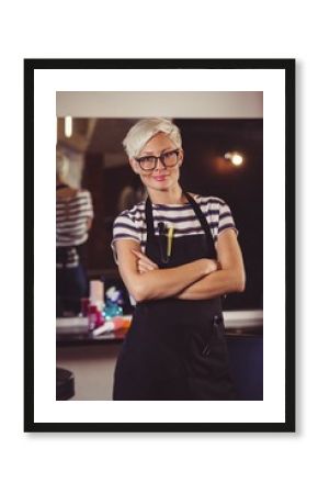 Female hairdresser standing with arm crossed at a salon