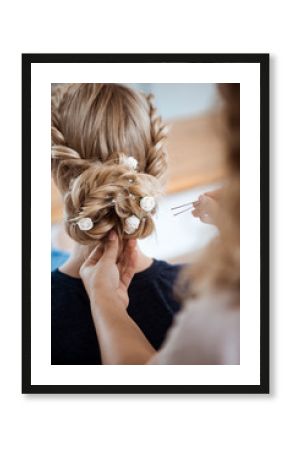 Female hairdresser making hairstyle to blonde girl in beauty salon.