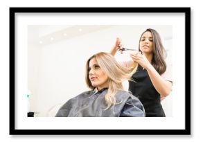 Hairdresser cutting some hair tips of a blonde woman in a salon