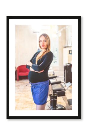 young woman pregnant indoors at work standing looking camera - working mother, girl power, determination concept