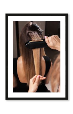professional hairdresser making a gauffer hairdo of a woman with long hair in a beauty salon. concept of stylist training