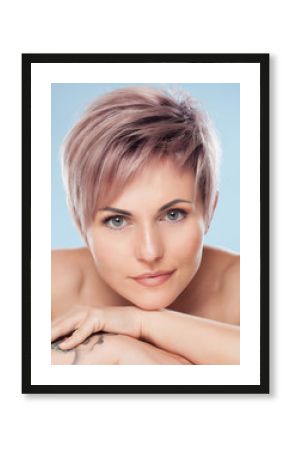 Portrait of a beautiful blonde woman with beautiful make-up and short haircut after dyeing hair in a hairdressing salon on a pink background.