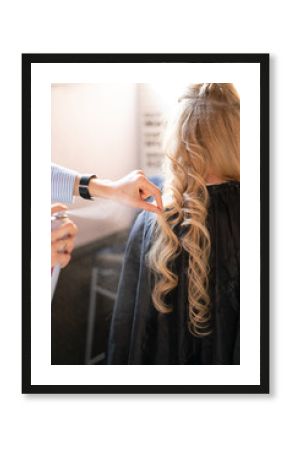 beautiful adult blonde client sits in a chair while a hairdresser master in the salon does her hair with a corrugation and a Perm