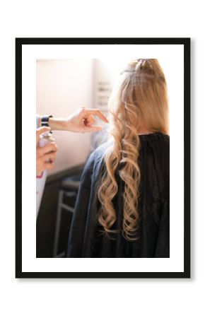 beautiful adult blonde client sits in a chair while a hairdresser master in the salon does her hair with a corrugation and a Perm