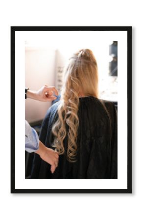 beautiful adult blonde client sits in a chair while a hairdresser master in the salon does her hair with a corrugation and a Perm