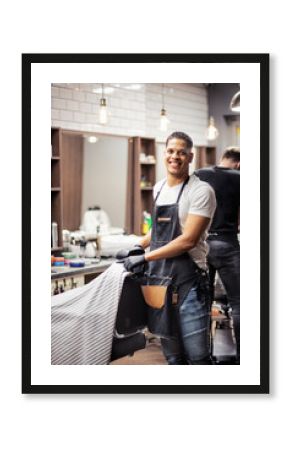 Young hispanic haidresser and hairstylist standing in barber shop.