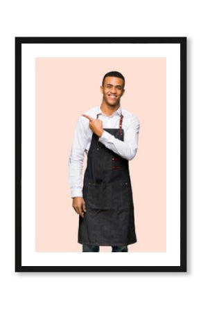Young afro american barber man pointing to the side to present a product on isolated background