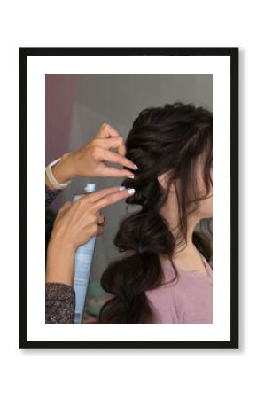 Hairstylist fixes textured tress using hair spray. Hairdressing services. Process of creating hairdo. Hairdresser makes hairstyle to client. Beauty industry