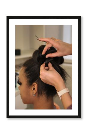 Hands of  professional female hairstylist make an evening hairstyle for her client. Hairdressing services. Creating hairstyles. Process of hair styling. Beauty industry