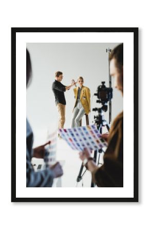 selective focus of hairstylist doing hairstyle to stylish model and producer with photographer on backstage