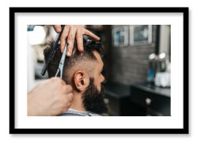 Good looking bearded man visiting hairstylist in barber shop.