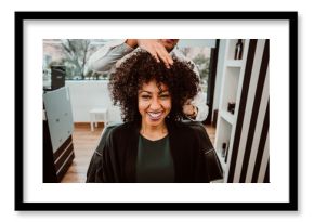 Beautiful latin woman with short curly brown hair getting a treat at the hairdresser. Latin hairdresser working her afro hair. Lifestyle