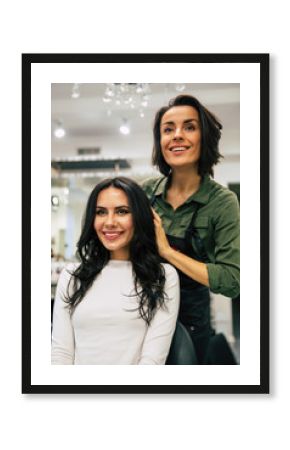 Pretty as a picture. Brunette young women and her hairstylist are looking at her reflection in the mirror in a hairdressing salon.