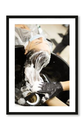 Hairdressing services during the coronavirus. Hands of hairdresser washing head of woman in mask. Hairdresser washing head of woman