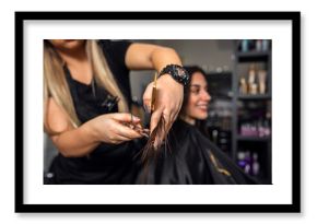 Female hairdresser makes hairstyle on young brunette  woman in salon cutting hair with scissors.