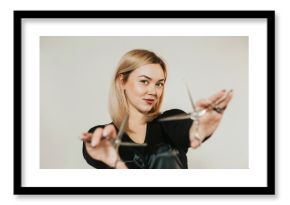 close-up portrait of a female hairdresser of European appearance. Hands are extended in front of you. Scissors in hand. Light hair color.