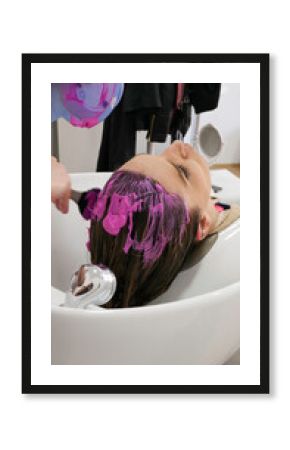 Hair treatment in a hair salon. Apply the pink mixture on the hair of the customer.
