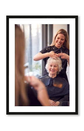 Senior Woman Having Hair Cut By Female Stylist In Hairdressing Salon