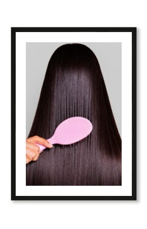 Combing a woman's hair with a pink brush