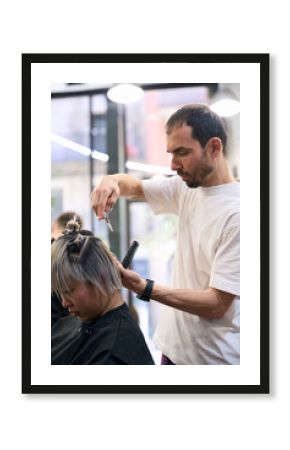 Hairdresser cutting hair of young woman in salon