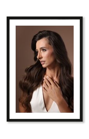 Hair styling. Beautiful woman with wavy long hair on brown background